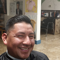 A man showcasing his hairstyle, inside a room with posters and chairs