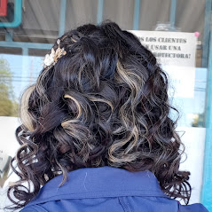 A woman showcasing her curly, and well-styled hair in a room.