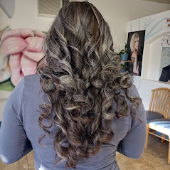 A woman showcasing her long, curly, and well-styled hair in a room.