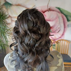 A woman showcasing her long, curly, and well-styled hair in a room.