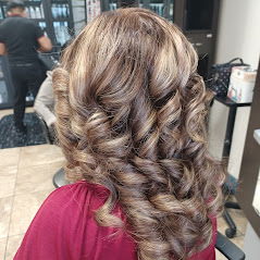 A close-up of beautifully styled wavy, blonde hair with a salon background