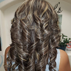 A close-up of wavy, blonde hair, styled beautifully with a salon background.